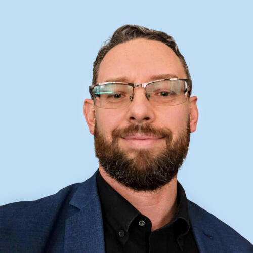 Michael Plis - Founder of Cyberkite Michael Plis, Founder and IT Cybersecurity Professional at Cyberkite, wearing glasses and a blue suit jacket.